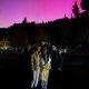 group of people with aurora behind with mountains