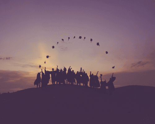 graduates at sunset throwing up caps